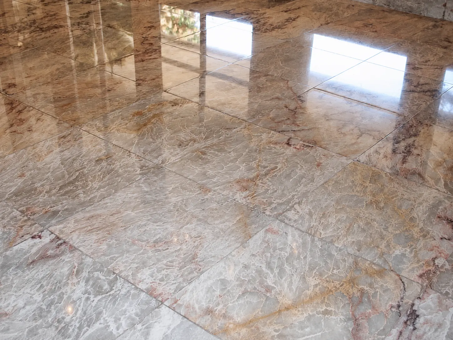 High-gloss brown veined marble floor reflecting natural window light after polishing