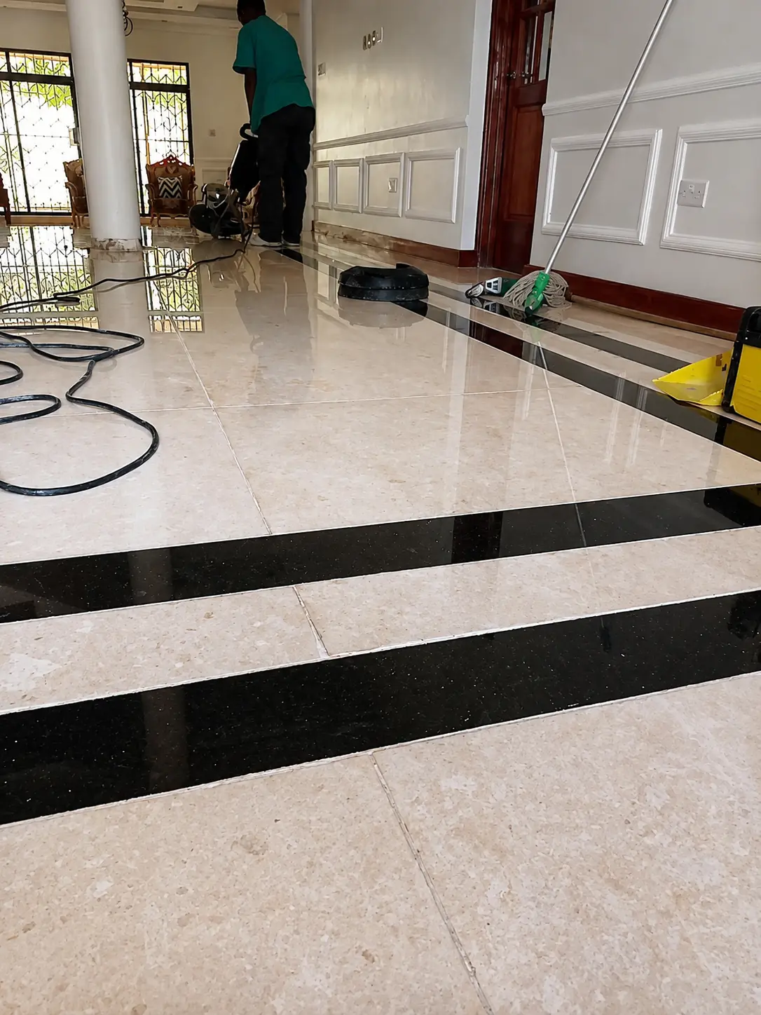 Sakafu technician completing machine polishing on a marble floor