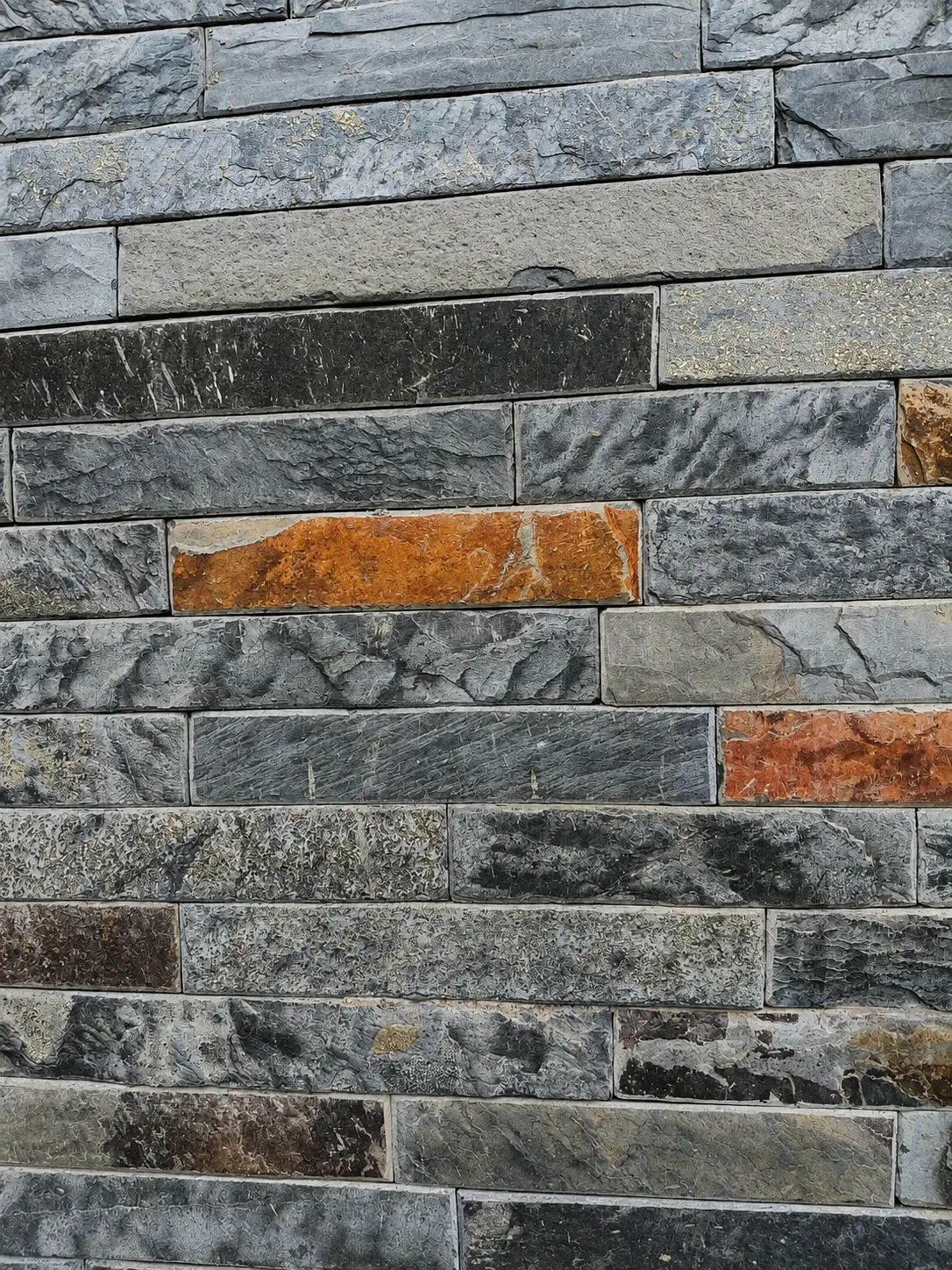 Mixed grey stacked-stone cladding with warm natural accent pieces